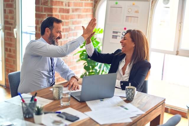 Two workers high-fiving each other for excellent work in digital marketing, mobile app development, and web design (Philippines).